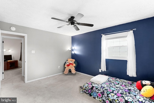 bedroom featuring ceiling fan, a textured ceiling, baseboards, and carpet floors