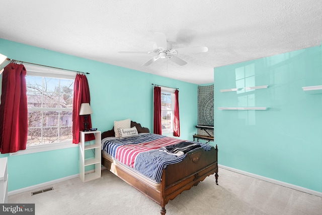 carpeted bedroom with ceiling fan, baseboards, visible vents, and a textured ceiling