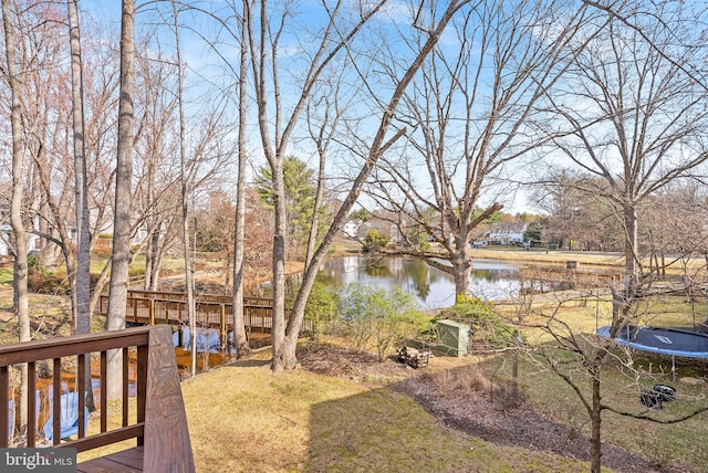 view of yard with a deck with water view and a trampoline