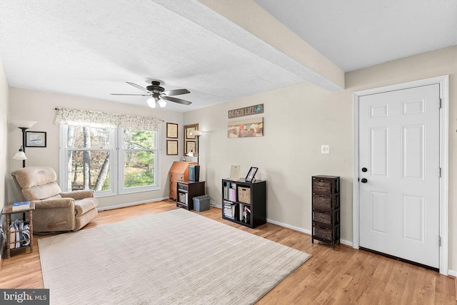 sitting room with a textured ceiling, baseboards, light wood-type flooring, and ceiling fan