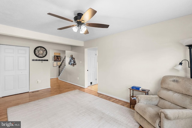 living area with baseboards, wood finished floors, and stairs