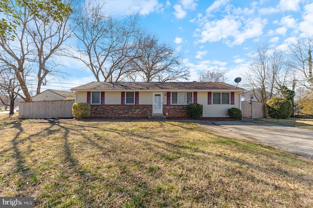 view of front of home with aphalt driveway, brick siding, a front yard, and fence