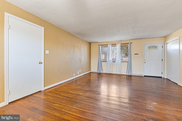 unfurnished living room with baseboards, a textured ceiling, and wood finished floors