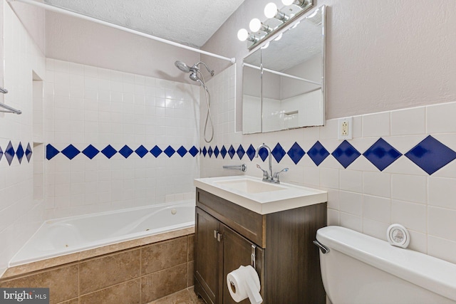 full bath with vanity, tiled shower / bath combo, a textured ceiling, tile walls, and toilet