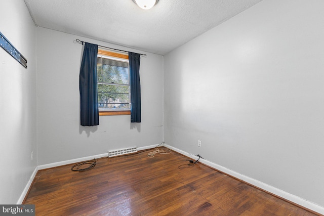 spare room with visible vents, a textured ceiling, baseboards, and wood finished floors