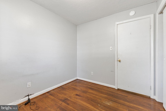 empty room with wood finished floors, baseboards, and a textured ceiling