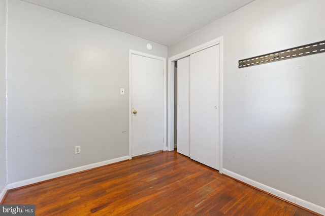 unfurnished bedroom featuring a closet, baseboards, and wood finished floors