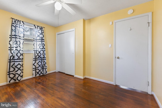 unfurnished bedroom featuring a closet, a ceiling fan, baseboards, and wood-type flooring