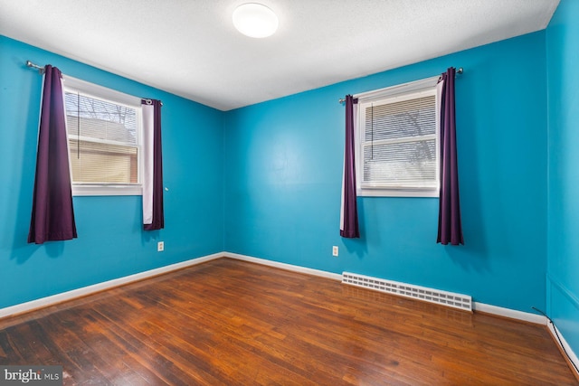 spare room featuring baseboards and wood finished floors