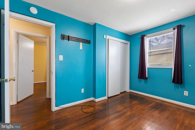 unfurnished bedroom with a closet, baseboards, and wood finished floors