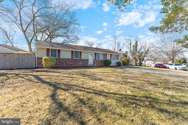 ranch-style home featuring a front yard, fence, and brick siding