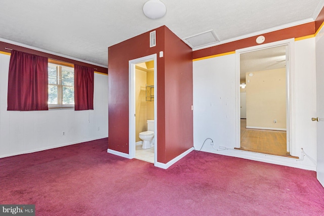 unfurnished bedroom featuring visible vents, attic access, crown molding, and carpet floors