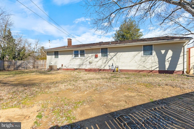 back of house featuring central AC unit, a chimney, and fence