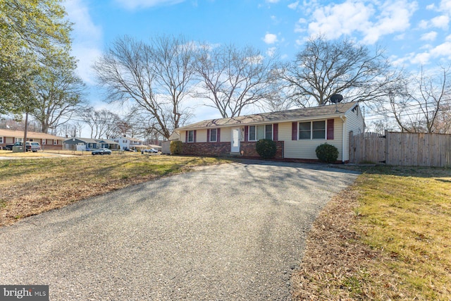 view of front of house featuring a gate, fence, a front lawn, aphalt driveway, and brick siding