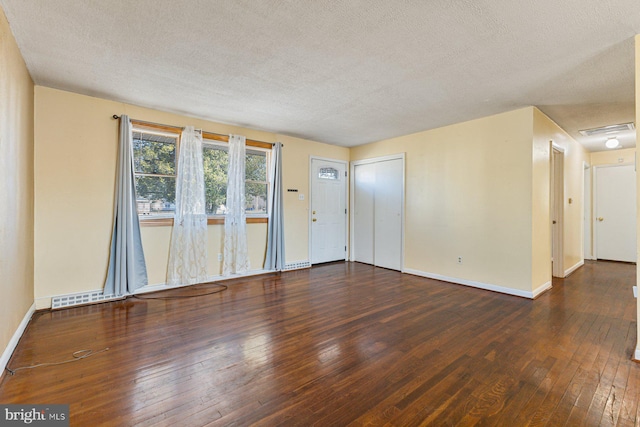 unfurnished living room featuring hardwood / wood-style floors, baseboards, and a textured ceiling