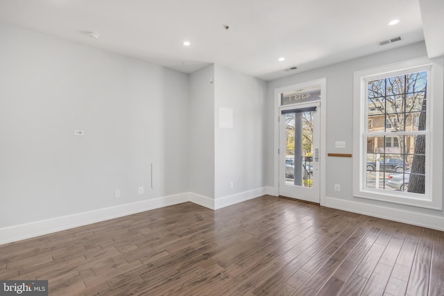 empty room featuring recessed lighting, dark wood-style floors, visible vents, and baseboards