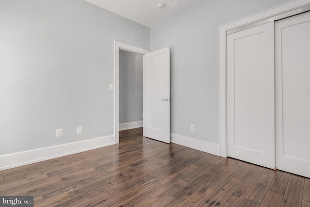 unfurnished bedroom with wood finished floors, baseboards, and a closet