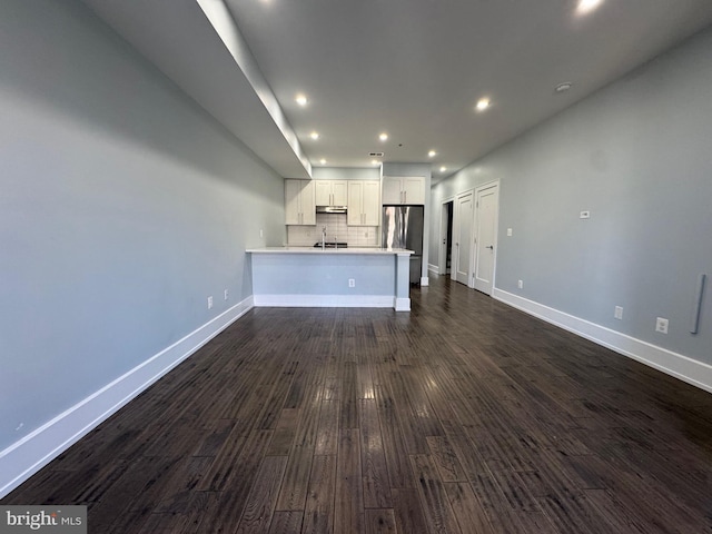 unfurnished living room featuring recessed lighting, baseboards, dark wood-style floors, and a sink