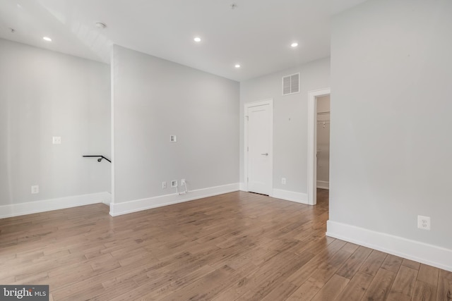 empty room with recessed lighting, wood finished floors, visible vents, and baseboards