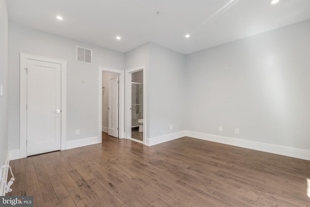 unfurnished bedroom featuring visible vents, ensuite bath, wood finished floors, recessed lighting, and baseboards