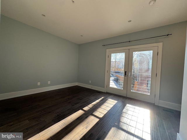 empty room with dark wood finished floors, french doors, and baseboards