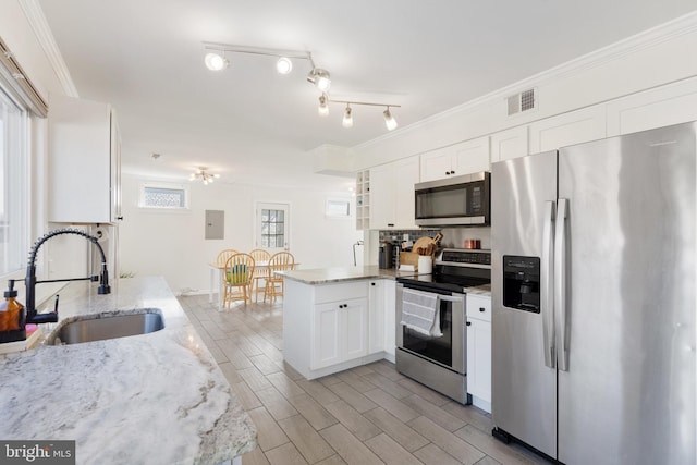 kitchen with visible vents, crown molding, a peninsula, stainless steel appliances, and a sink