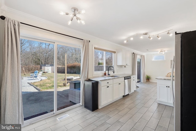 kitchen with a sink, appliances with stainless steel finishes, ornamental molding, and white cabinets