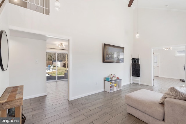 living area featuring baseboards, crown molding, wood finish floors, and a towering ceiling