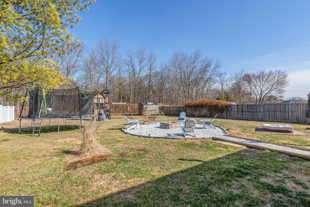 view of yard featuring a patio, a fire pit, a trampoline, and a fenced backyard