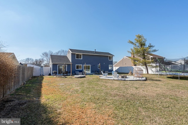 back of property with a yard, a trampoline, and a fenced backyard