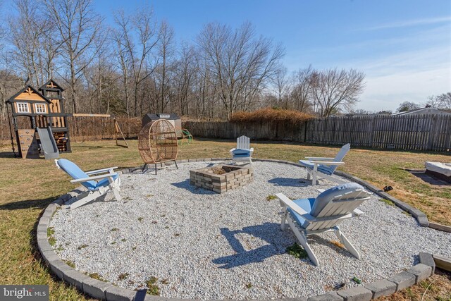 view of yard with fence, a fire pit, a patio, and a playground