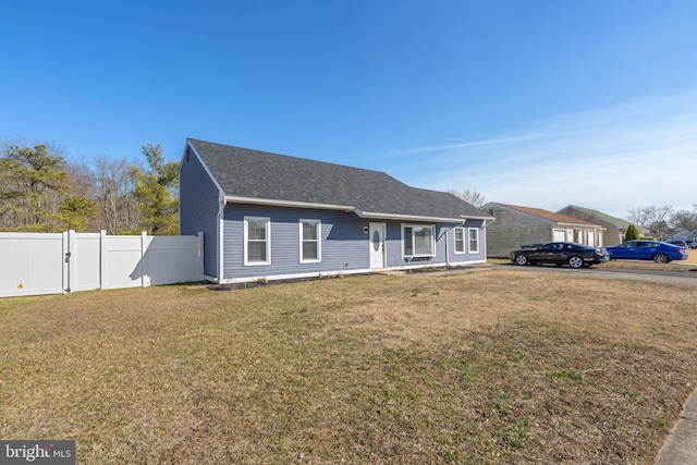 view of front of house with a front lawn, fence, and roof with shingles