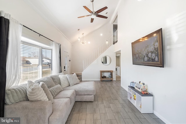 living room with baseboards, wood finished floors, stairs, and ceiling fan with notable chandelier