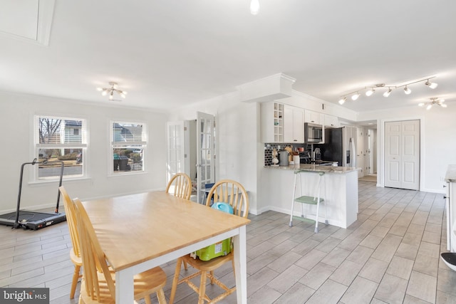 dining room featuring baseboards, crown molding, and light wood-style floors