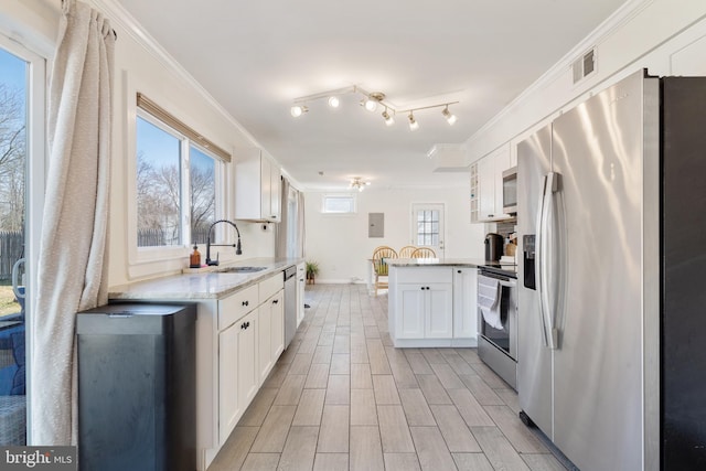 kitchen featuring visible vents, a sink, stainless steel appliances, a peninsula, and crown molding