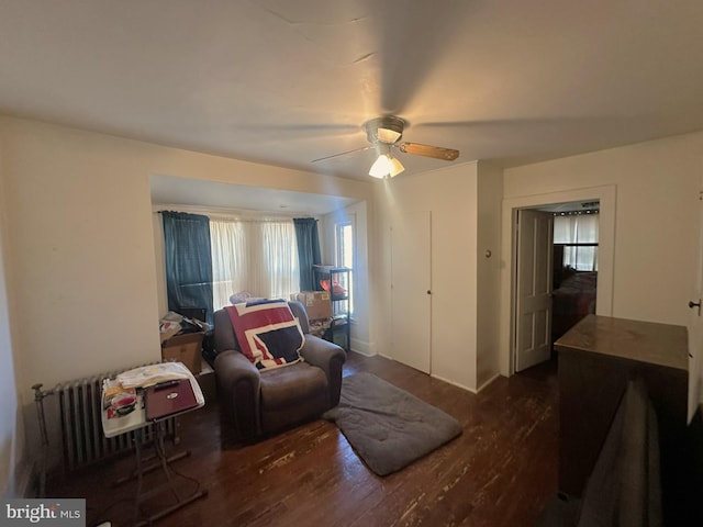 living area with a ceiling fan, radiator heating unit, and wood finished floors