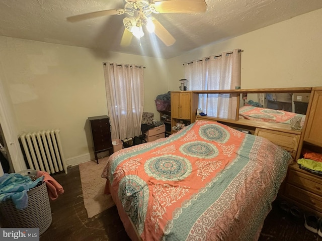 bedroom featuring ceiling fan, radiator, a textured ceiling, and wood finished floors