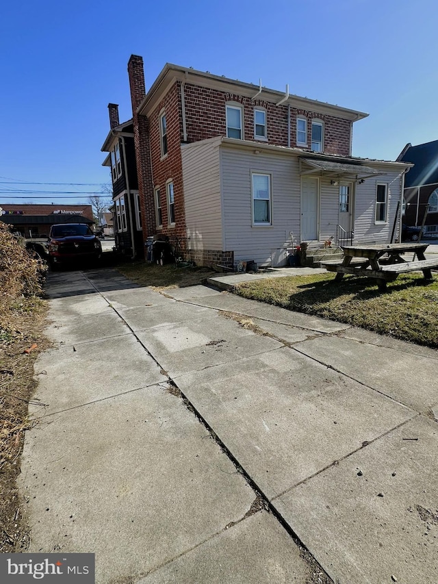 back of property with brick siding and a chimney