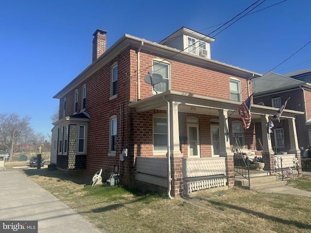 traditional style home featuring covered porch, brick siding, and a chimney