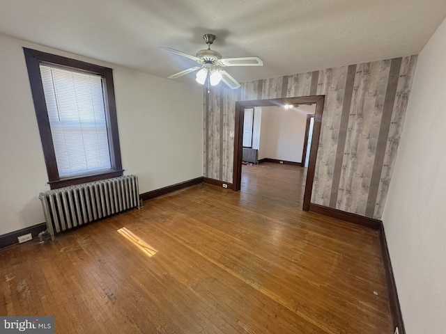 spare room with radiator, baseboards, and hardwood / wood-style floors