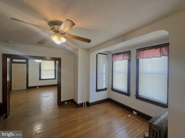 spare room with baseboards, radiator, wood finished floors, and a textured ceiling