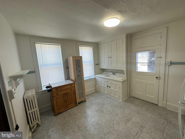 kitchen with marble finish floor, light countertops, radiator heating unit, and a sink