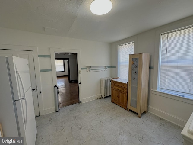 bathroom featuring radiator heating unit, baseboards, marble finish floor, and a textured ceiling