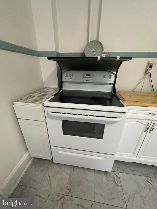 kitchen with baseboards, white cabinetry, marble finish floor, and white range with electric cooktop