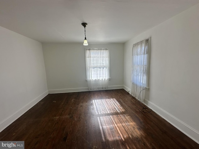 empty room with baseboards and wood-type flooring