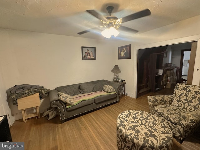 living room featuring a ceiling fan, wood finished floors, and a textured ceiling