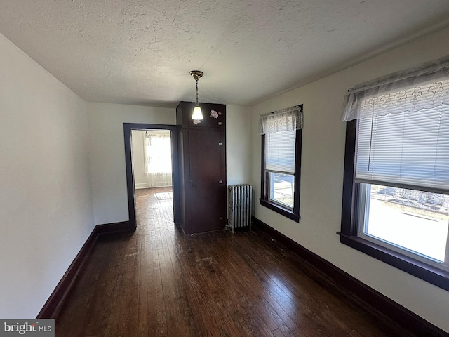 unfurnished dining area with radiator heating unit, dark wood-style floors, baseboards, and a healthy amount of sunlight