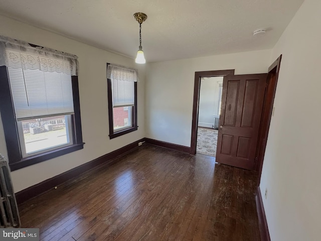 unfurnished room featuring dark wood-type flooring and baseboards