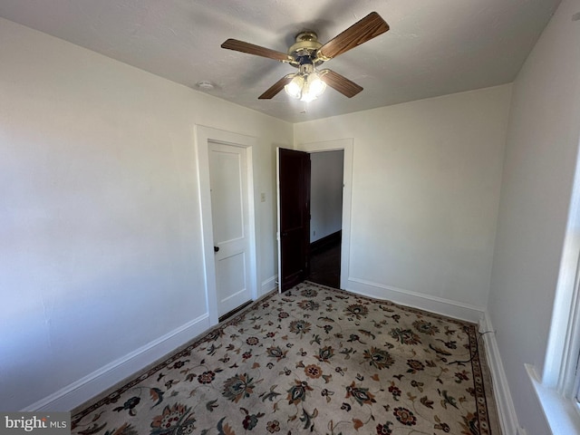 empty room featuring light colored carpet, a ceiling fan, and baseboards