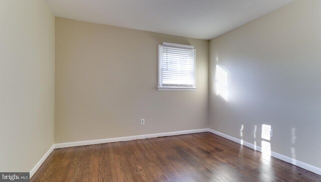 spare room featuring baseboards and wood finished floors